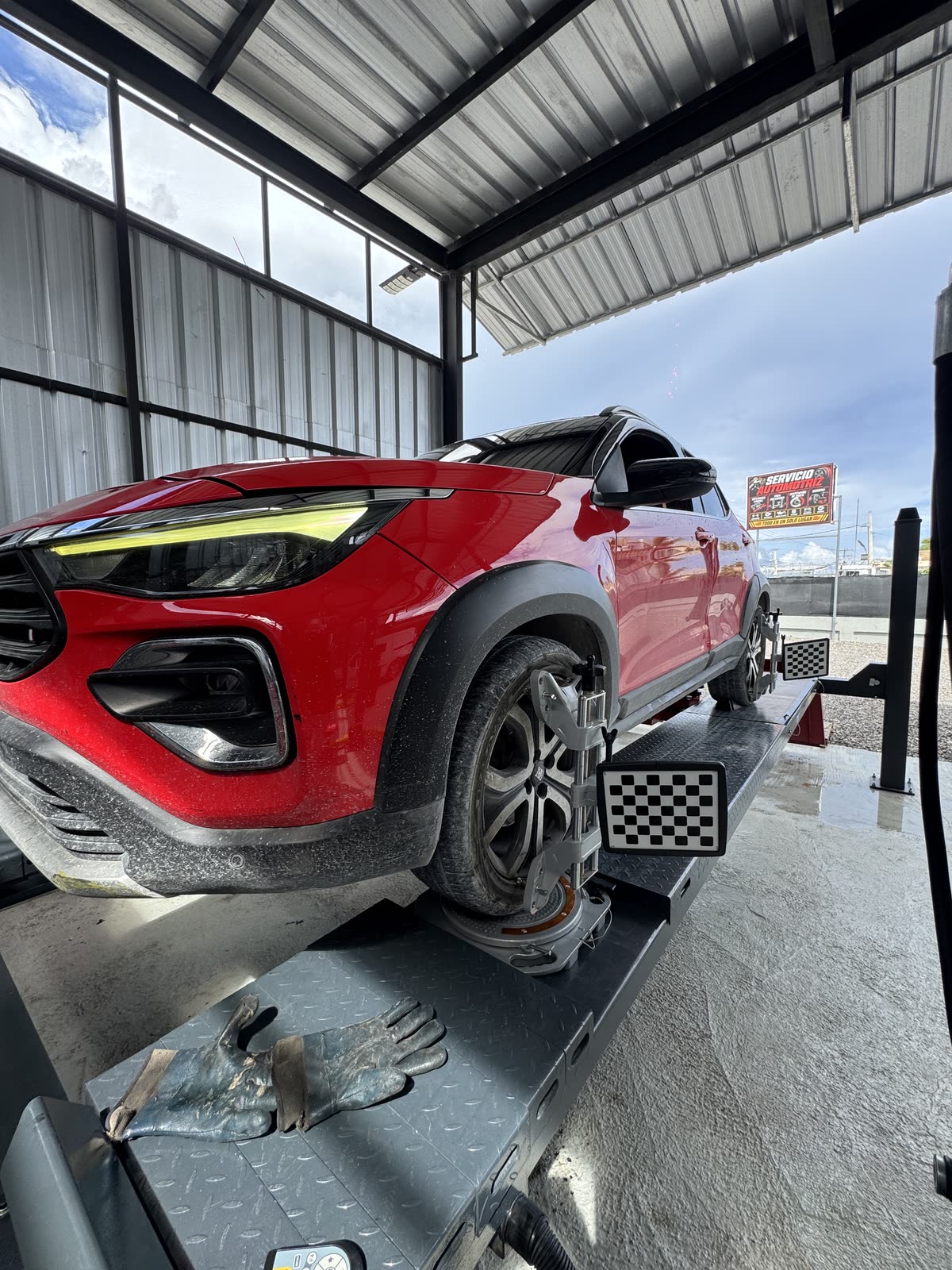Carro rojo en la alineadora con las placas puestas en las ruedas