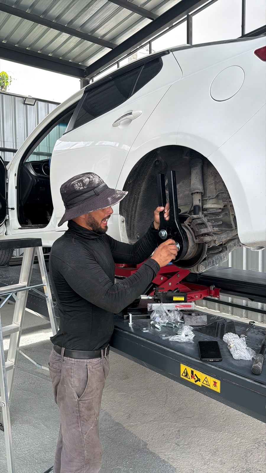 Mecánico trabajando en la rueda delantera de un carro blanco